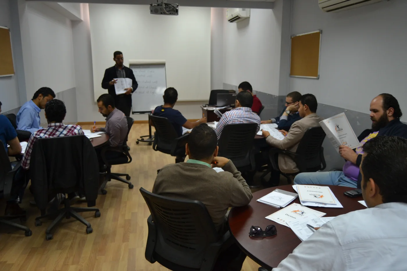 Dr Osama Qandil leading a B.TECH training session with participants working around the room