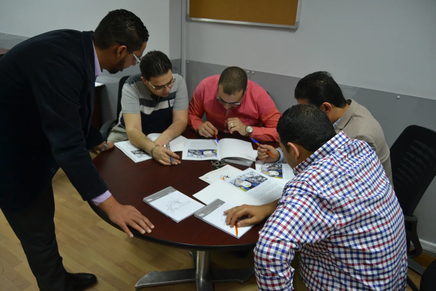 Dr Osama Qandil working with a small group around a table during training